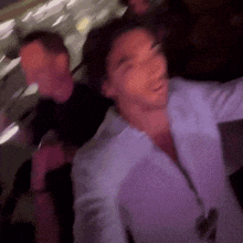 a blurry picture of a man in a white shirt dancing in a dark room .