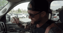 a man is sitting in a car eating food with a fork