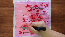 a person is painting a cherry blossom tree with red flowers
