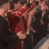 a man in a red jacket is dancing in a crowd of people .