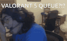a man wearing a headset is sitting in front of a computer with the words valorant 5 queue