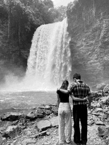 a man and a woman are looking at a waterfall