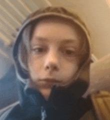 a young boy wearing a hooded jacket and headphones is looking at the camera .