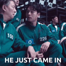 a man with the number 226 on his jacket sits next to another man with the number 100 on his jacket