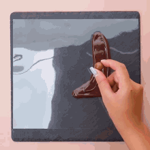 a person holding a piece of chocolate on a slate surface