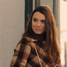 a woman wearing a plaid coat is smiling