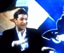 a man in a suit and white gloves stands in front of a blue and white umbrella