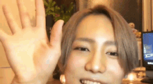 a young man is waving his hand in front of a computer screen .