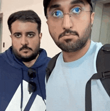 two men are posing for a picture together and one has glasses on .