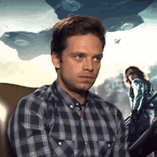 a man in a plaid shirt is sitting in a chair with a woman in a blue shirt behind him .