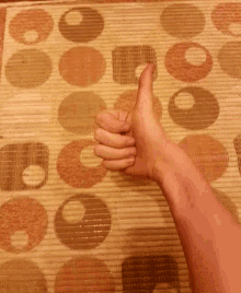 a person is giving a thumbs up in front of a rug with circles on it
