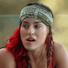 a woman with red hair and a bandana on her head looks surprised