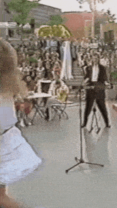 a man in a suit is playing a guitar in front of a crowd .