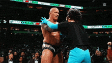 a wrestler is hugging another wrestler in a wrestling ring .