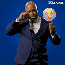 a man in a suit and tie is holding a fox deportes emoticon