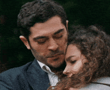 a man in a suit is hugging a woman in a white shirt