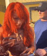 a woman with red hair is looking at her phone while a man wearing a black hat with the word army on it looks on