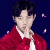 a young man wearing a red jacket and a white shirt is making a gesture with his finger