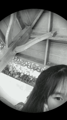 a black and white photo of a woman 's face with a wooden roof in the background