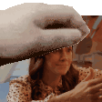 a woman wearing a polka dot shirt is holding a towel on her head .