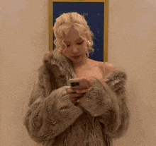 a woman in a fur coat looking at her phone