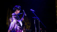 a woman in a kimono is singing into a microphone