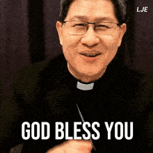 a man with glasses and a priest collar is smiling and says god bless you