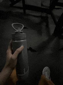 a person is holding a gray bottle with the word tupperware on it