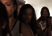 a group of women are standing in a dark room and one has the number 1r on her shirt