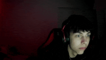 a young boy wearing headphones is sitting in front of a computer screen .