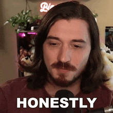 a man with long hair and a beard says " honestly " in front of a microphone