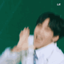 a man in a white shirt and tie is making a funny face with his hands .