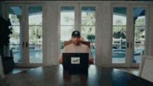 a man is sitting at a table using a laptop computer in a living room .