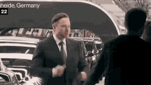 a man in a suit and tie is shaking hands with another man in front of a sign that says heide germany