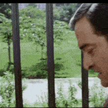 a man is standing in front of a fence looking out .