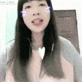 a woman wearing headphones and a pink shirt has a heart shaped necklace around her neck