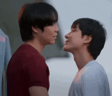 a couple of young men are kissing each other on the forehead .