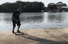 a man wearing a shirt that says infinity is riding a skateboard near a body of water
