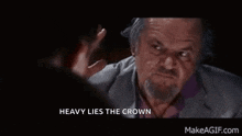 a man with a beard is talking to another man and the words heavy lies the crown are visible