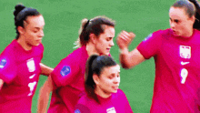 a group of female soccer players wearing pink jerseys are playing a game on a field .