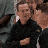 a man wearing a black cavs shirt is talking to another man