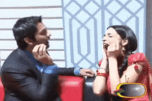 a man in a suit and a woman in a red dress are sitting on a couch