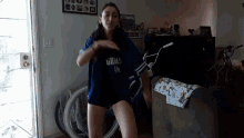 a woman is dancing in a living room while wearing a shirt that says girls la