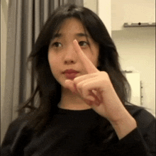 a woman in a black shirt is pointing her finger at something