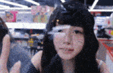 a woman with long black hair is looking through a glass window .