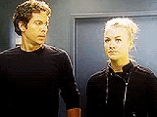 a man and a woman are standing next to each other in a hallway .