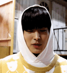 a man wearing a yellow and white sweater with a white hood on his head