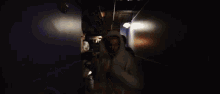 a man in a hoodie is standing in a dark room with his arms outstretched .