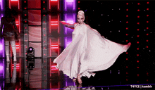 a woman in a long white dress is dancing on stage .
