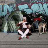 a man is sitting on the sidewalk in front of a tent with the word n on it